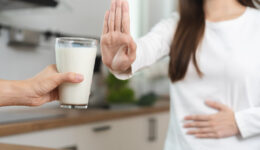 An Asian Woman Pushing Her Hand Out Declining a Glass of Milk While Holding Her Stomach What Are the Worst Foods for IBS?