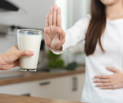 An Asian Woman Pushing Her Hand Out Declining a Glass of Milk While Holding Her Stomach What Are the Worst Foods for IBS?