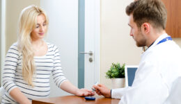 Doctor Sitting at a Desk Measuring a Woman’s Blood Sugar What Are 10 Warning Signs of Diabetes